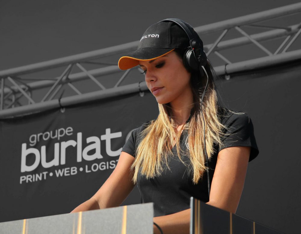 La DJ Sara Costa mixe lors d'un meeting aérien devant un fond de scène signé groupe Burlat